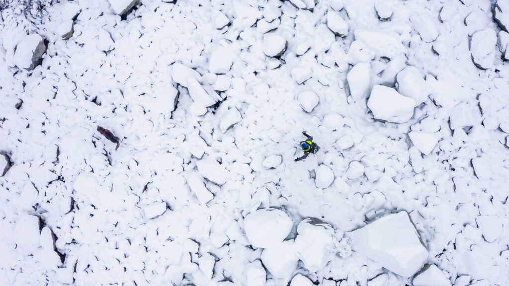 foto z dronu - záchranár so psom na zasneženom teréne 