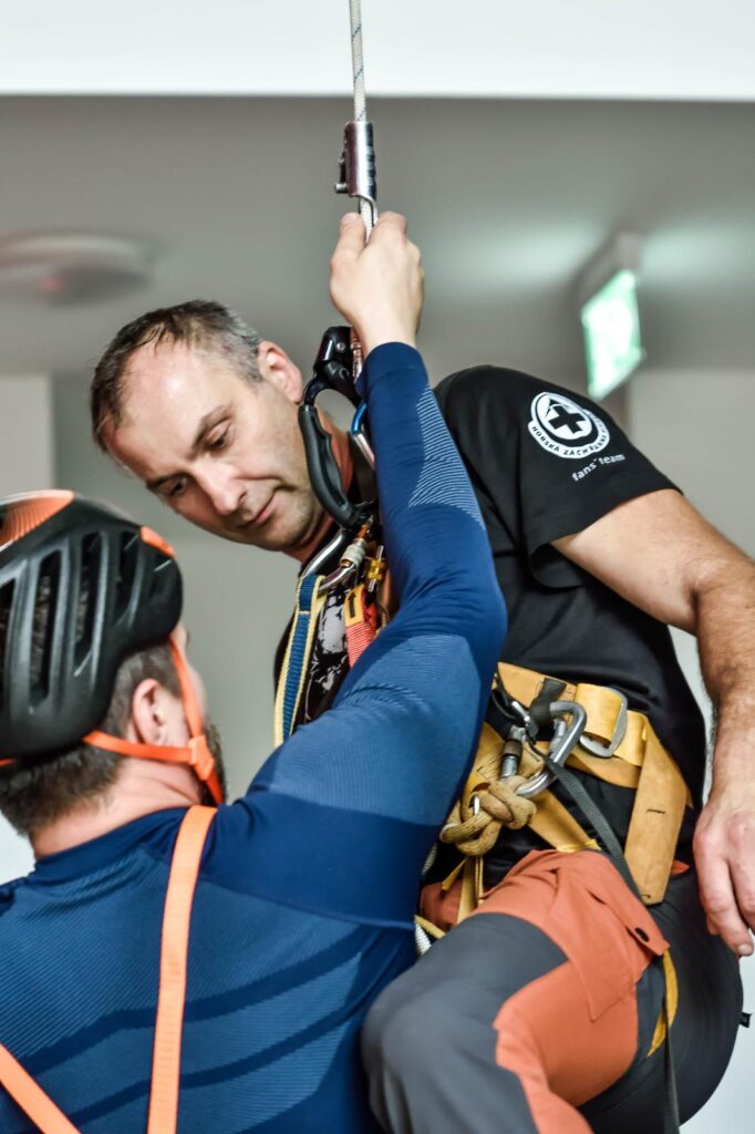 účastník memoriálu v lezeckom sedáku, naviazaný na lane, pripravený na žumarovanie 