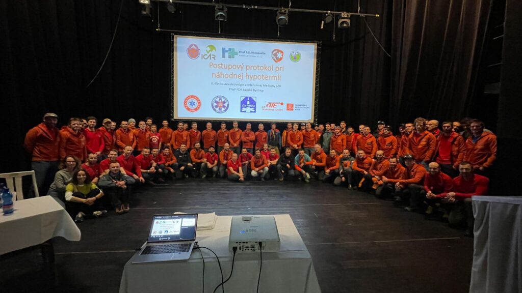 Horskí záchranári a účastníci seminára na pódiu pod plátnom