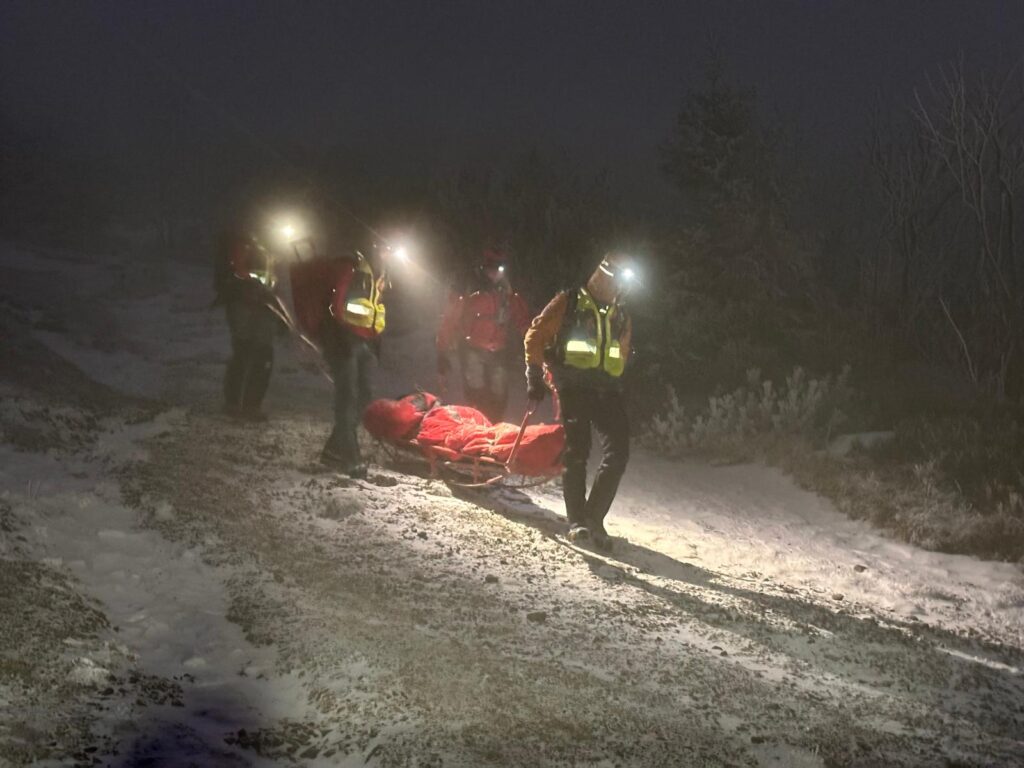 Záchranári znášajú pacienta po zasneženom chodníku