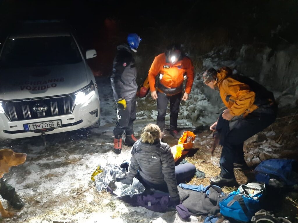 Záchranári ošetrujúci pacientku pri terénnom vozidle