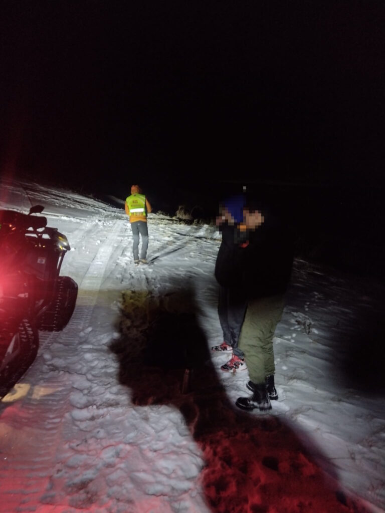 Záchranár, štvorkolka HZS a dvaja mladí turisti v noci na zasneženej ceste