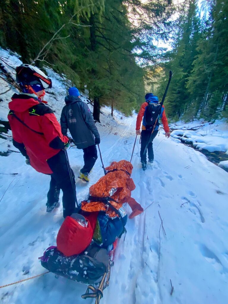 Horskí záchranári transportujú pacienta na saniach zasneženým terénom