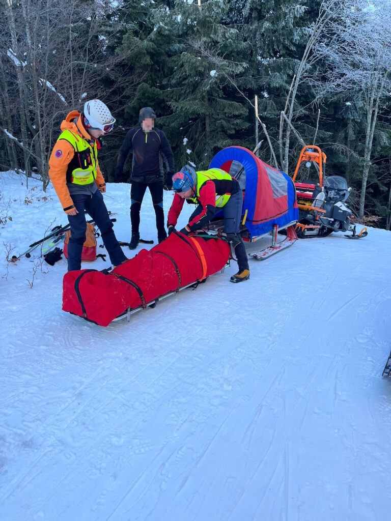 Horskí záchranári s nabaleným pacientom na saniach