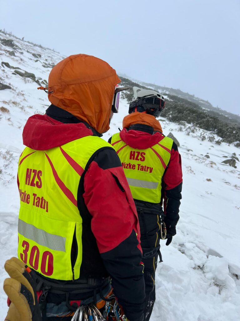 ilustračná foto - dvaja horskí záchranári v zime v teréne jedného zo žľabov, na sebe majú reflexné záchranárske vesty s nápisom HZS Nízke Tatry