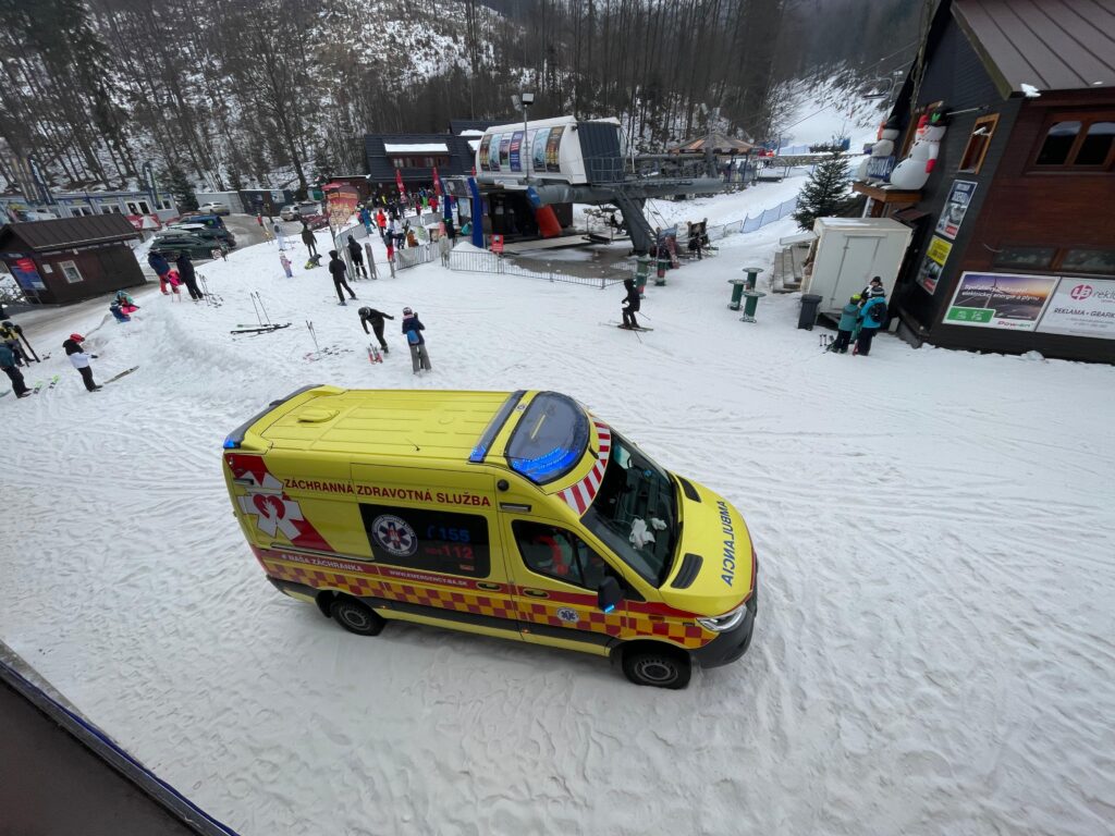 žlté vozidlo RLP pri údolnej stanici lanovky na Dedovke, v okolí lyžiari