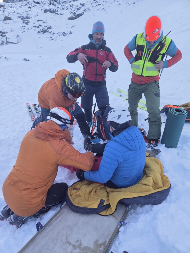 ilustračný obrázok, záchranári HZS ošetrujú v zimných podmienkach zraneného lyžiara