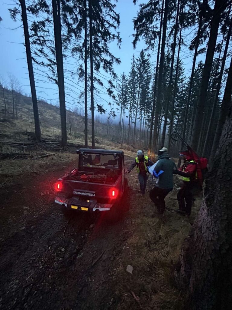 záchranári HZS akurát ukončujú sprevádzanie pacientky k štvorkolke, na fotografií záchranári s pacientkou pri štvorkolke, nachádzajú sa v lese, v pozadí hmla 