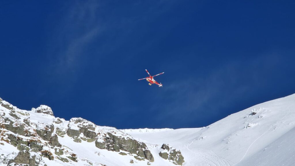 vrtuľník TOPR-u (Sokol) nad hrebeňom, v pozadí modré nebo