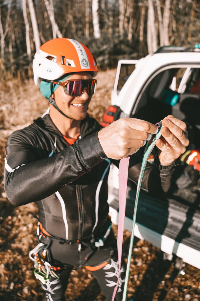 pretekár si lepí skialpinistické pásy na lyže 