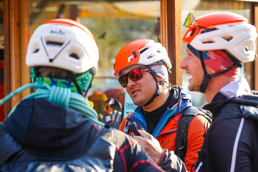 debata medzi pretekármi pred štartom - na fotografii traja pretekári, prilby na hlavách 