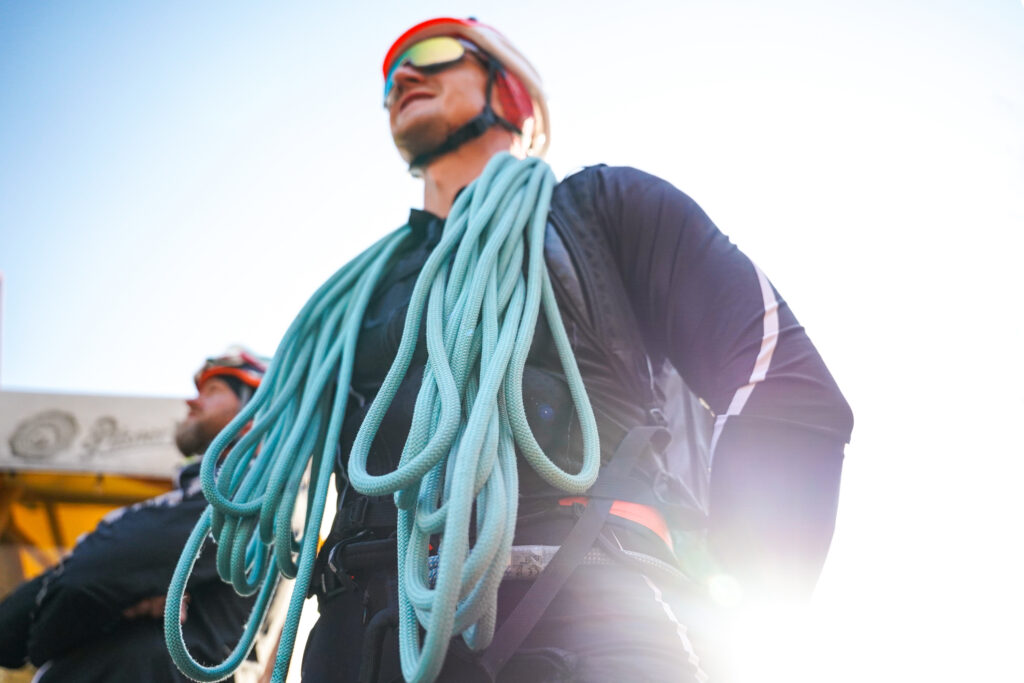 pretekár v prilbe s pripraveným modrým lanom, lano položené na pleciach 