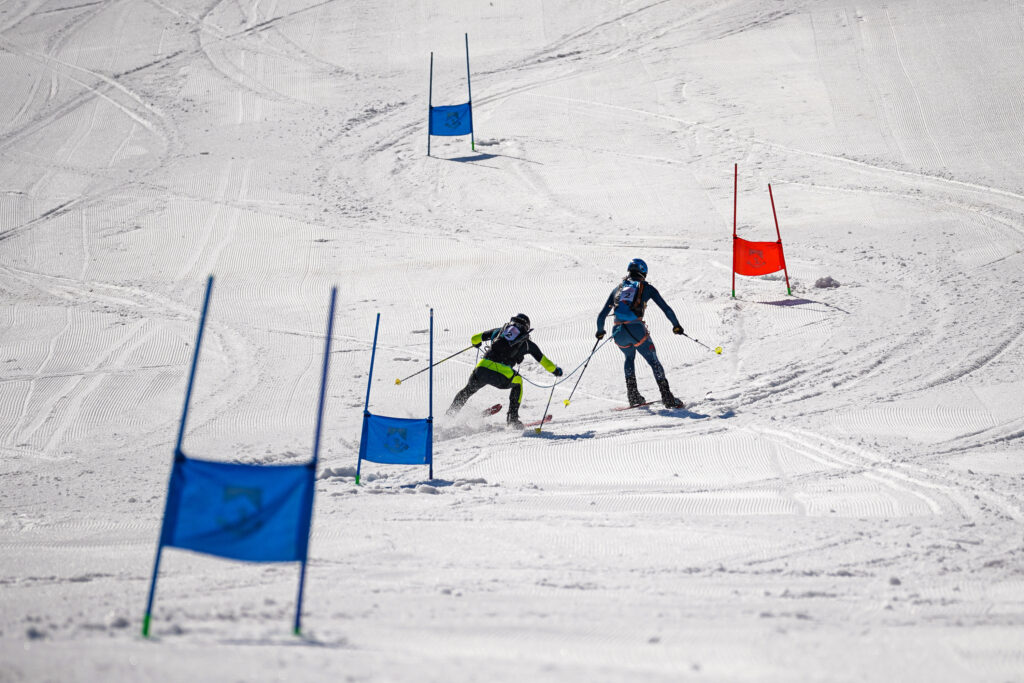 dvojica pretekárov zachytená pri obrovskom slalome naviazaná na lane medzi bránkami 