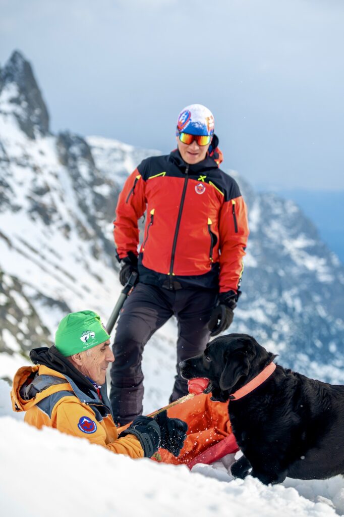 záchranársky pes a záchranári pri výcviku v lavíne