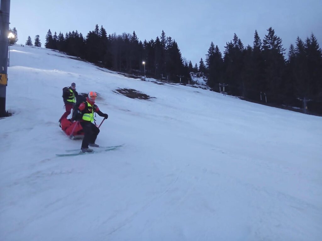 Záchranári HZS na saniach transportujú dole zjazdovkou zranenú skialpinistku