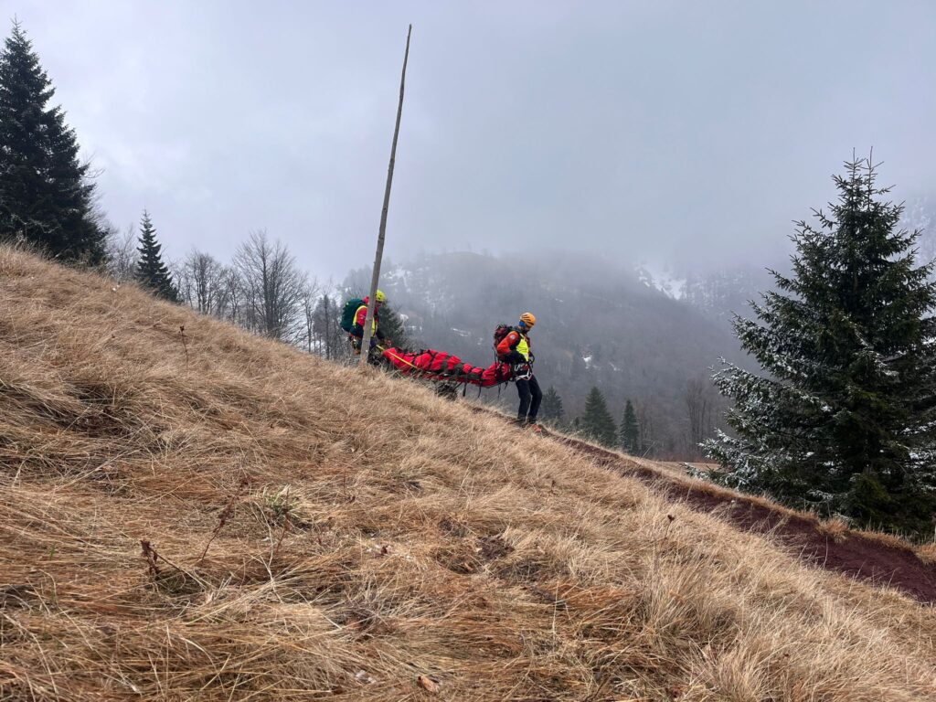 Záchranári s pacientom v nosidlách pri zostupe z chaty