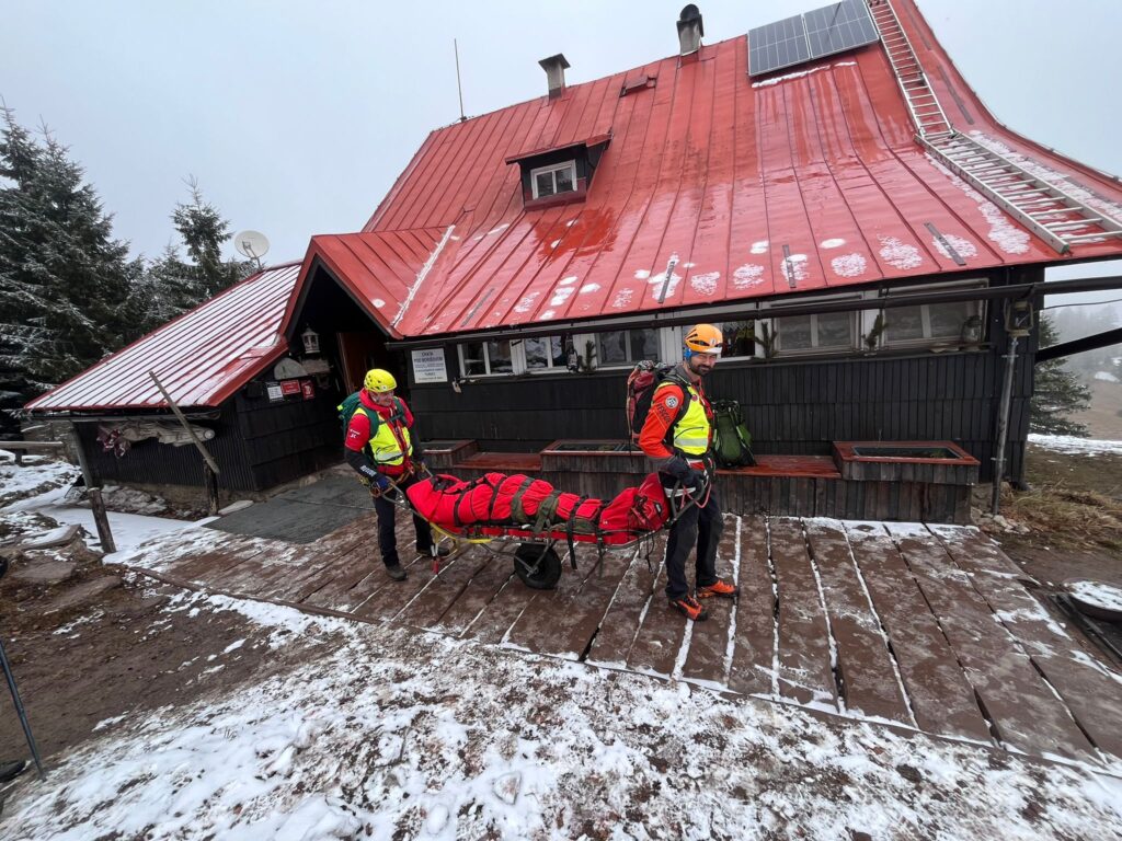 Záchranári s pacientom v nosidlách pred chatou
