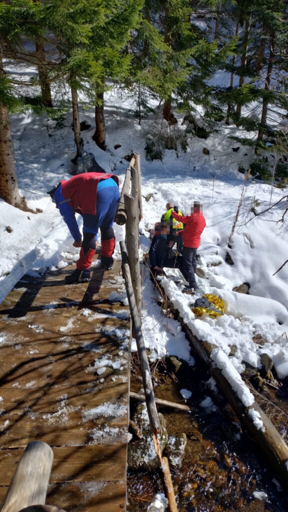 Horskí záchranár pri ošetrovaní pacienta pri horskom potoku