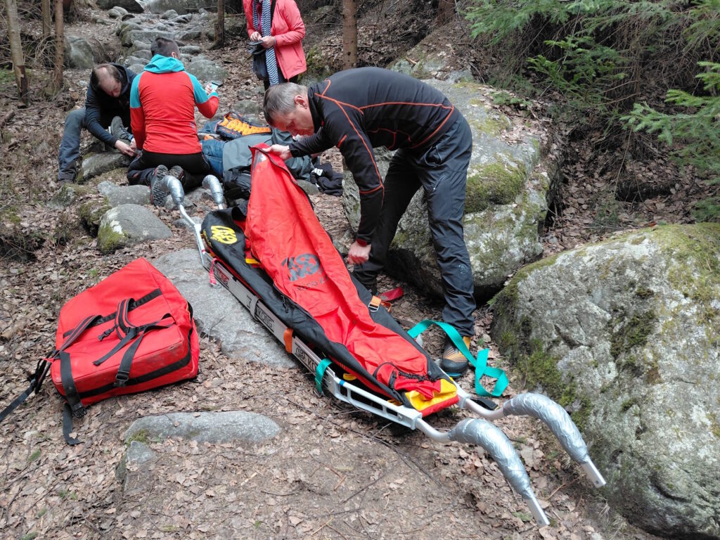 záchranár HZS na TZCH pripravuje na transport nosidlá, ďalší dvaja záchranári ošetrujú ležiaceho pacienta 