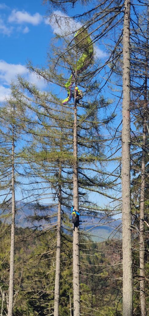 záchranár HZS spúšťa pomocou lanovej techniky uviaznutého paraglajdistu zo stromu