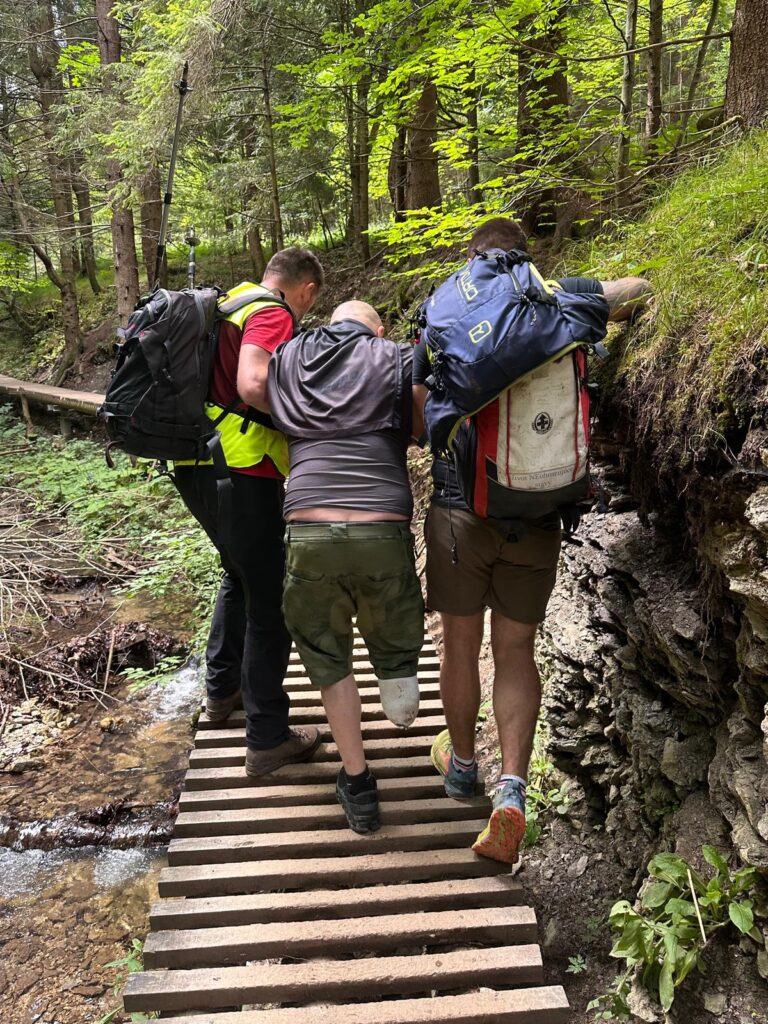 Horskí záchranári podopierajú turistu pri zostupe tiesňavou